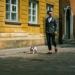 A man walks his Jack Russell on a cobblestone street in Warsaw's historical district.