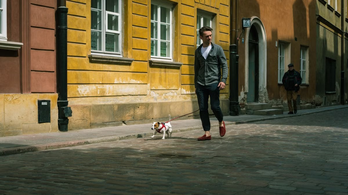 A man walks his Jack Russell on a cobblestone street in Warsaw's historical district.